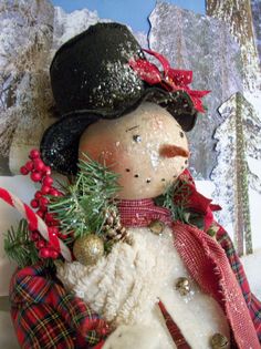 a snowman with a hat and scarf on it's head is holding a pine branch