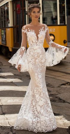 a woman in a wedding dress standing on the street