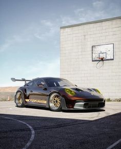 a black sports car parked in front of a basketball hoop on the side of a building