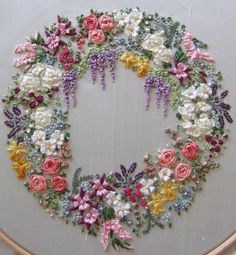 a cross - stitch wreath with flowers on it in the shape of a letter o