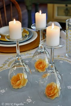 three wine glasses with candles in them sitting on a table