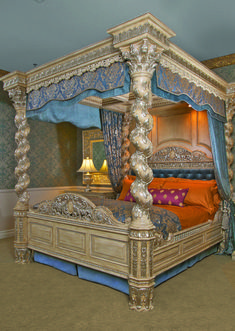 an ornate bed with blue and gold decor in a bedroom setting, it is made up to look like a four poster bed