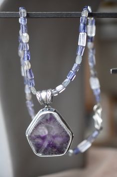 "Large amethyst trapiche crystal in set in a silver bezel on a silver backing. The setting is embellished with silver granules and hangs from a vintage silver bail of braided wire . the pendant hangs on a necklace of iolite and labradorite and crystal beads. The closure is a silver \"S\" hook." Silver Rondelle Gemstones For Jewelry Making, Artisan Amethyst Gemstone Beads Jewelry, Unique Amethyst Gemstone Bead Jewelry, Artisan Amethyst Jewelry With Natural Stones, Artisan Jewelry With Natural Amethyst Stones, Unique Amethyst Gemstone Beaded Jewelry, Silver Jewelry With Gemstone Beads, Silver Rondelle Gemstone Jewelry, Amethyst Gemstone Bead Pendant Jewelry