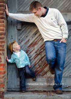 a man leaning up against a wall next to a little boy with his hand on the door