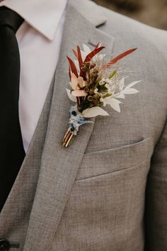 a man wearing a suit and tie with a boutonniere on his lapel