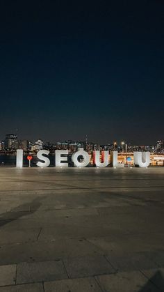 the sign is lit up at night in front of a cityscape with lights