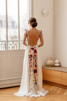 a woman standing in front of a window wearing a dress with floral print on it