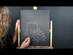 a woman is drawing on a blackboard with white chalk