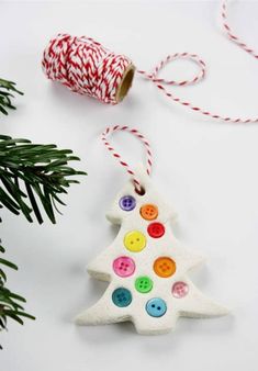 a christmas tree ornament with buttons and spools of yarn next to it