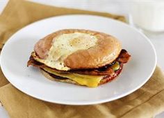 a breakfast sandwich on a white plate next to a glass of milk and napkins