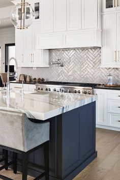 a large kitchen with white cabinets and marble counter tops, along with an island in the middle