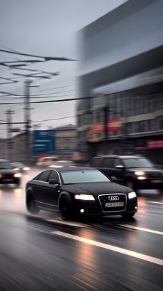 a black car driving down the street in front of other cars on a rainy day