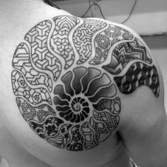 the back of a man's shoulder with an intricate tattoo design on his arm