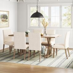 a dining room with white chairs and a rug