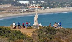 a group of people standing on top of a hill next to the ocean