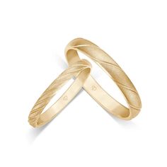 two gold wedding bands with wavy lines on each side, set in 18k yellow gold