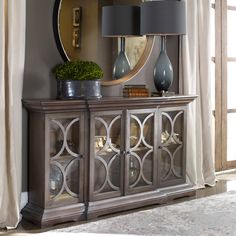 a large mirror sitting on top of a wooden cabinet next to a lamp and vase