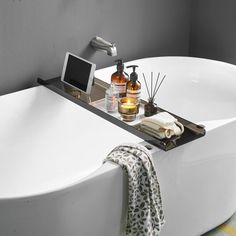 a white bath tub sitting next to a bathroom sink with soap dispensers on it