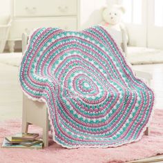 a crocheted blanket sitting on top of a wooden chair next to a teddy bear