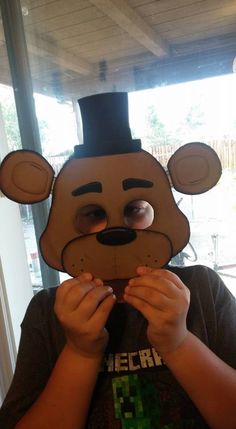 a person wearing a paper mask with a mouse on it's head and holding something in front of their face