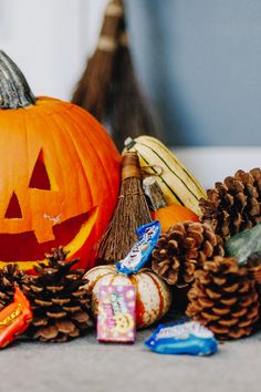 an orange pumpkin surrounded by candy and pine cones