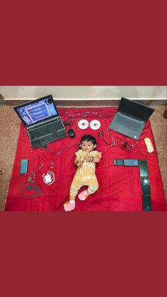 there is a small child laying on the floor next to laptops and other items