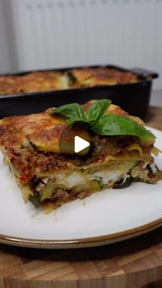 a white plate topped with lasagna covered in cheese and toppings next to a baking dish