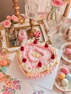 a heart shaped cake sitting on top of a table next to plates and cups filled with candy