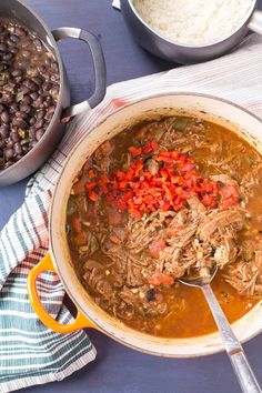 a pot filled with beans and meat next to other food on top of a table