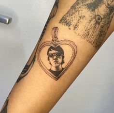 a woman's arm with a heart shaped photo on it and a keychain hanging from the wrist