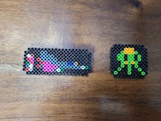 two pieces of perler bead art sitting on top of a wooden table next to each other