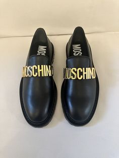 Crafted in Italy, these Moschino leather loafers are styled with goldtone logo hardware across the vamp. Leather upper Almond toe Slip-on style Leather sole Made in Italy Gold Loafers With Leather Sole For Business, Designer Gold Formal Loafers, Gold Leather Loafers With Leather Sole, Luxury Gold Loafers With Round Toe, Gold Leather Shoes For Business, Designer Gold Loafers For Work, Gold Loafers With Leather Sole, Gold Luxury Loafers For Office, Luxury Gold Loafers For Office