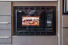 an advertisement on the front of a microwave oven in a kitchen with stainless steel cabinets