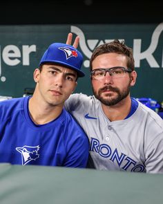 two baseball players pose for a photo in the dugout