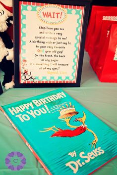 a dr seuss book and stuffed animal on a table with a sign that says, happy birthday to you