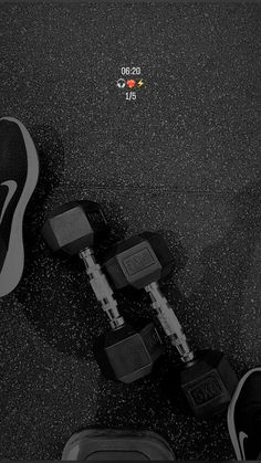 a pair of black and white shoes sitting on top of a floor next to two dumbbells