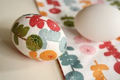 an egg sitting on top of a table next to a roll of fabric with flowers