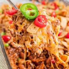 a spoon full of chili and cheese casserole on a plate with a fork