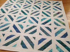 a blue and white quilt on top of a wooden floor