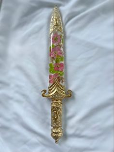 an ornate gold and pink flowered glass candle holder on a white sheet with flowers