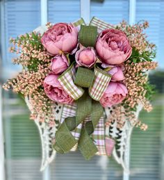 a bouquet of pink flowers hanging from the side of a door with ribbon on it