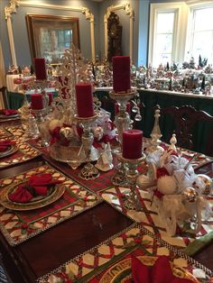 a dining room table set for christmas with red candles and candy canes on it