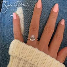 a woman's hand with a pink manicure and a diamond ring on it