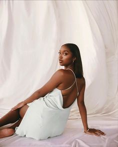 a woman sitting on top of a white sheet