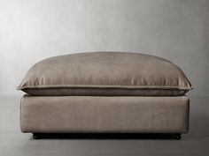 a large pillow sitting on top of a footstool in front of a wall