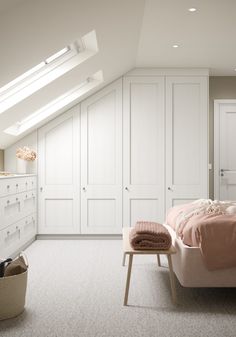 an attic bedroom with white closets and pink bedding, along with a skylight