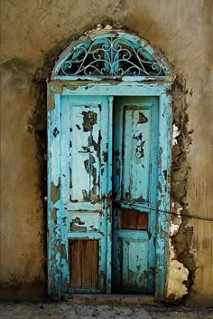 an old blue door on the side of a building with peeling paint and chipping