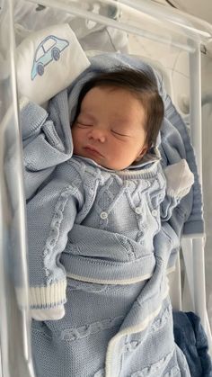 a baby is sleeping in a clear plastic box with his head tucked under the blanket