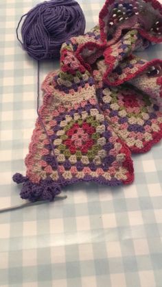 two crocheted grannys are laying on a checkered tablecloth with yarn