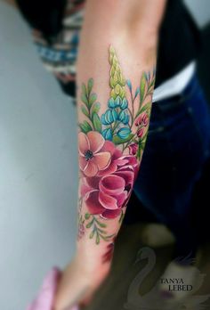 a woman's arm with flowers and leaves tattooed on her left arm, next to a pink shoe